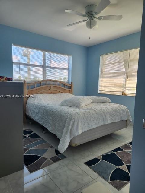 bedroom featuring tile patterned flooring, multiple windows, and ceiling fan