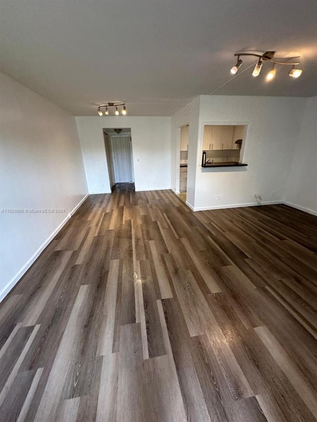 unfurnished living room with dark wood-type flooring and rail lighting