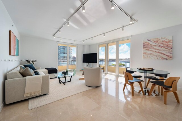 unfurnished living room with light tile patterned floors, sink, track lighting, and a water view