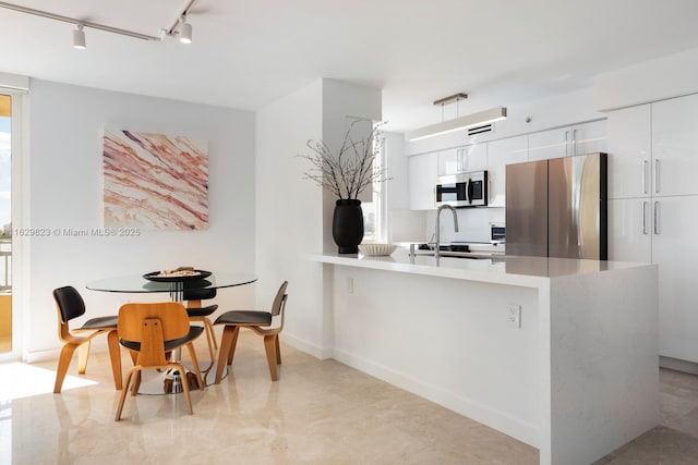 kitchen with stainless steel appliances, white cabinets, a sink, modern cabinets, and a peninsula