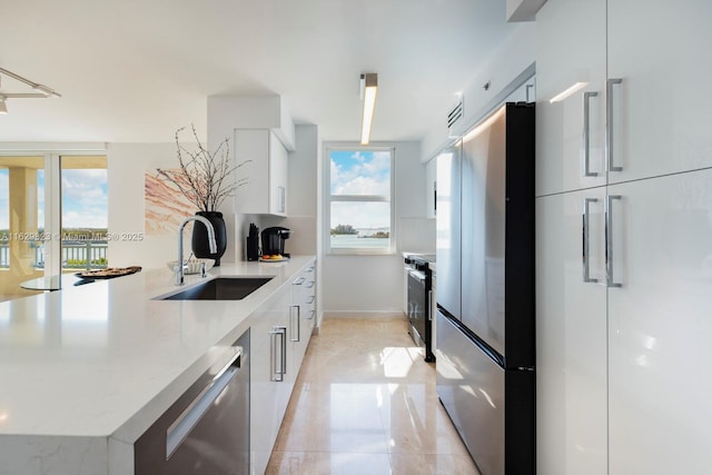 kitchen featuring plenty of natural light, stainless steel appliances, modern cabinets, and a sink