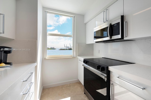 kitchen featuring tasteful backsplash, light countertops, stainless steel microwave, electric range, and white cabinets