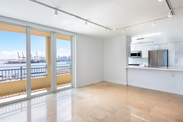 unfurnished living room with baseboards, rail lighting, a city view, floor to ceiling windows, and a sink