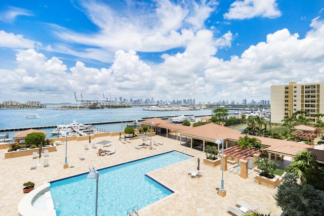 community pool with a water view, a patio area, and a view of city