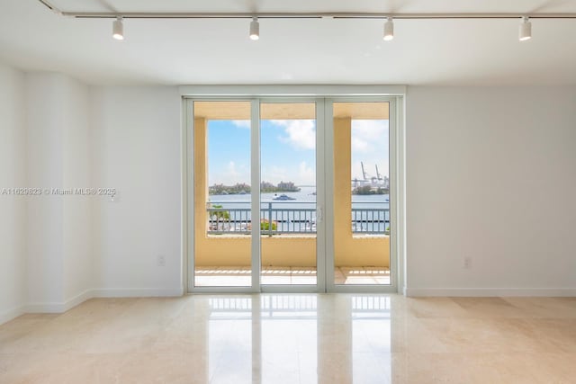 unfurnished room featuring tile patterned floors, rail lighting, and baseboards