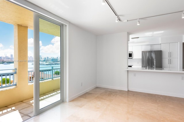 interior space with a view of city, baseboards, and track lighting