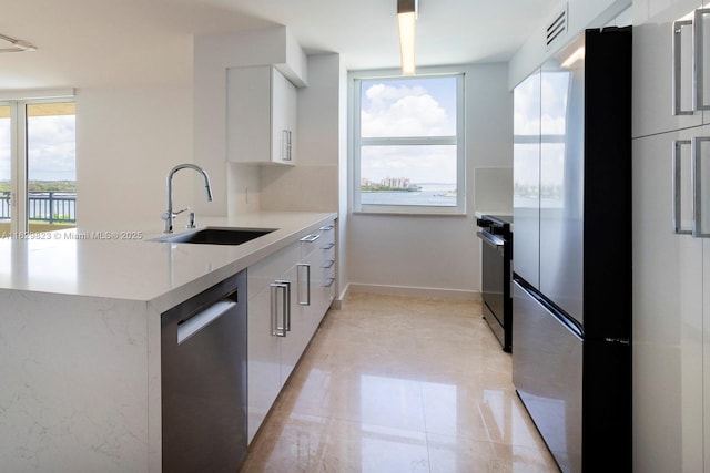 kitchen with visible vents, stainless steel dishwasher, a sink, modern cabinets, and range