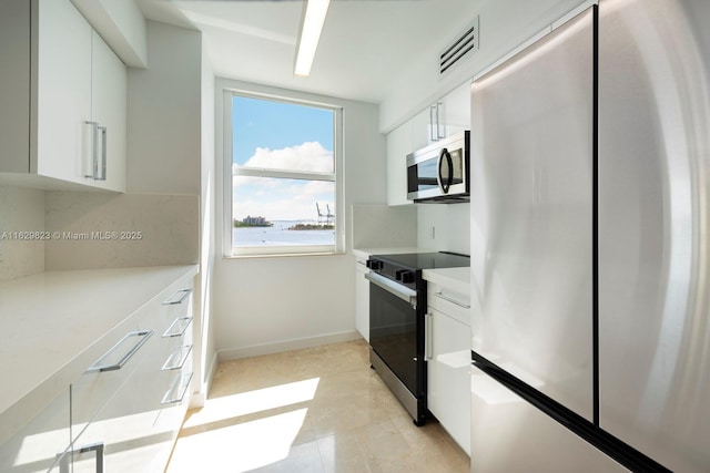 kitchen with stainless steel appliances, visible vents, baseboards, white cabinetry, and light countertops