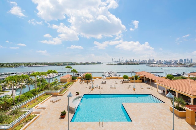 community pool with a view of city, a patio area, and a water view