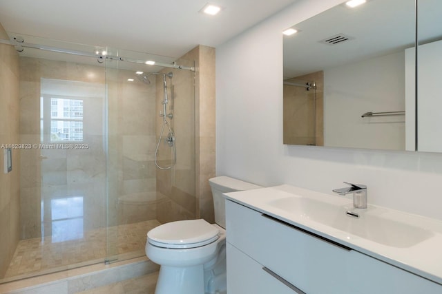 bathroom with visible vents, vanity, a shower stall, and toilet