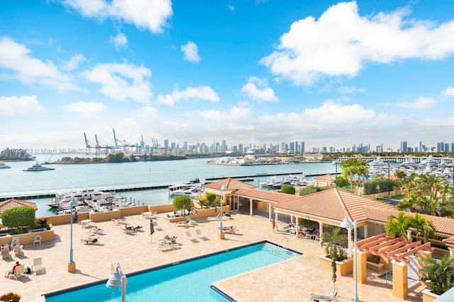 community pool featuring a view of city, a patio area, and a water view