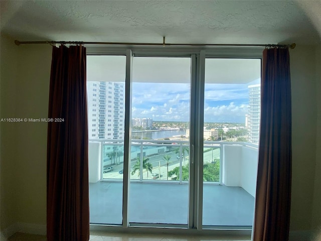 doorway to outside with plenty of natural light, a water view, and a textured ceiling