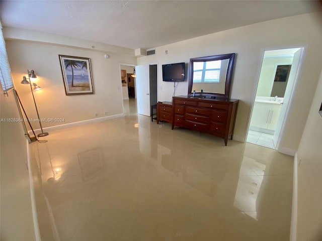 bedroom with light tile patterned floors, connected bathroom, and sink