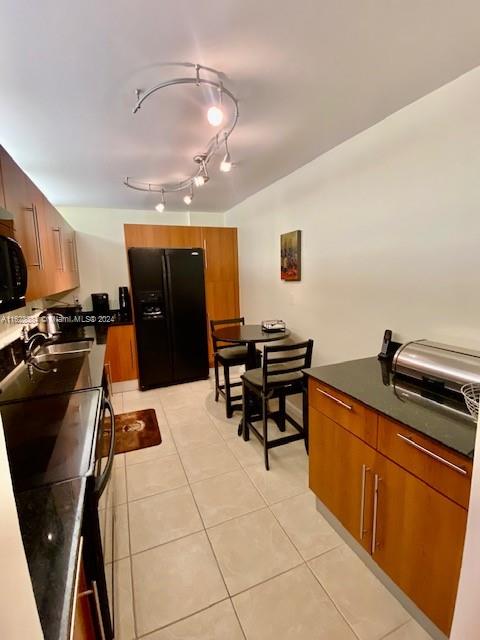 kitchen with light tile patterned flooring, sink, and black appliances