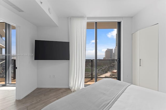 bedroom with light hardwood / wood-style flooring, access to exterior, and floor to ceiling windows