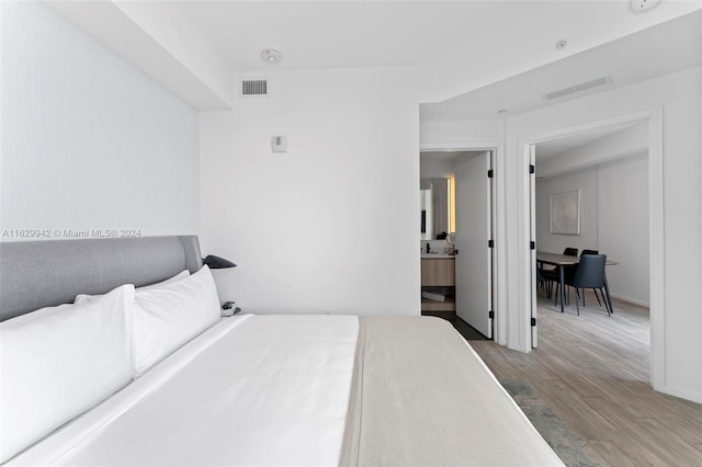 bedroom featuring wood-type flooring and ensuite bath