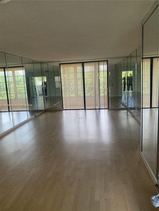 unfurnished room with floor to ceiling windows and hardwood / wood-style flooring