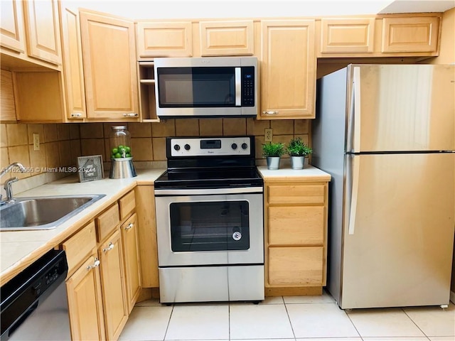 kitchen featuring appliances with stainless steel finishes, tasteful backsplash, sink, light brown cabinets, and light tile patterned floors