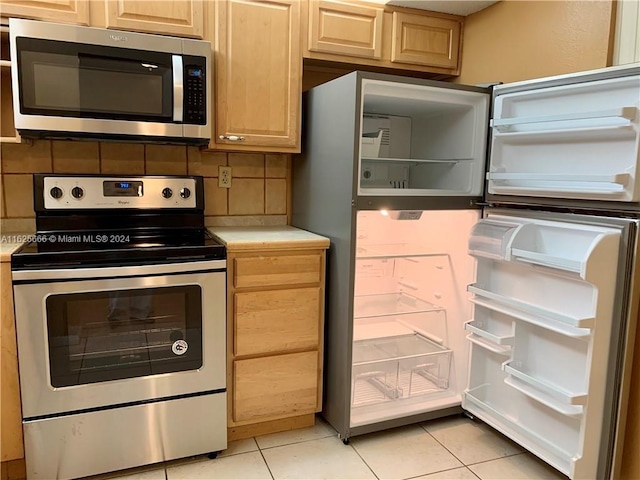 kitchen featuring light tile patterned flooring, appliances with stainless steel finishes, tasteful backsplash, and light brown cabinets