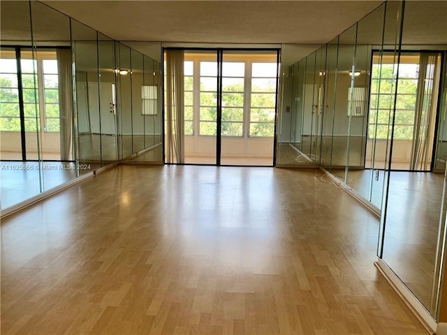 empty room featuring a wealth of natural light, expansive windows, and hardwood / wood-style floors