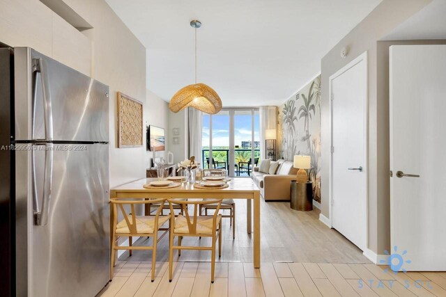 dining area featuring light wood-type flooring and a wall of windows