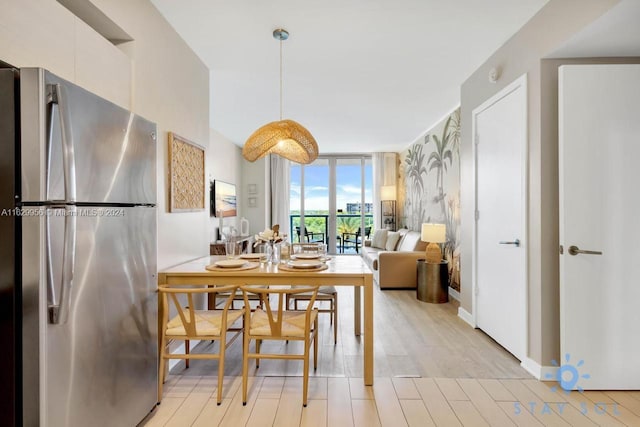 dining space with baseboards, light wood-style flooring, and floor to ceiling windows