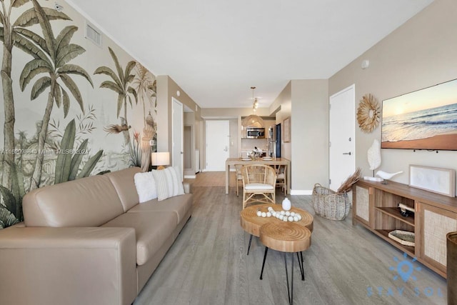 living room with light wood-type flooring, visible vents, and baseboards