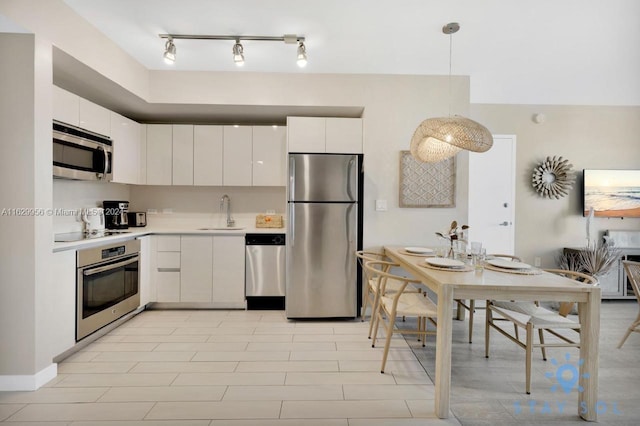 kitchen with stainless steel appliances, a sink, white cabinets, light countertops, and decorative light fixtures