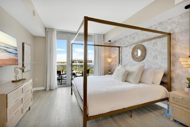 bedroom with access to exterior, floor to ceiling windows, light wood-style floors, and wallpapered walls