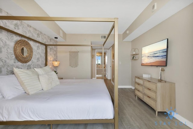 bedroom with baseboards, visible vents, and wood finished floors