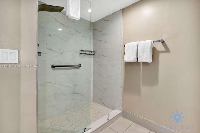 bathroom with a marble finish shower, baseboards, and tile patterned floors