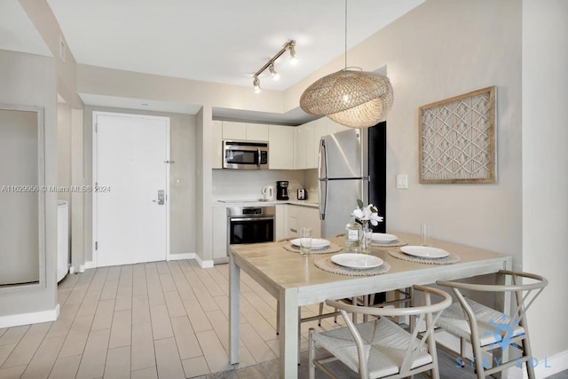 dining area featuring light wood finished floors, baseboards, and track lighting