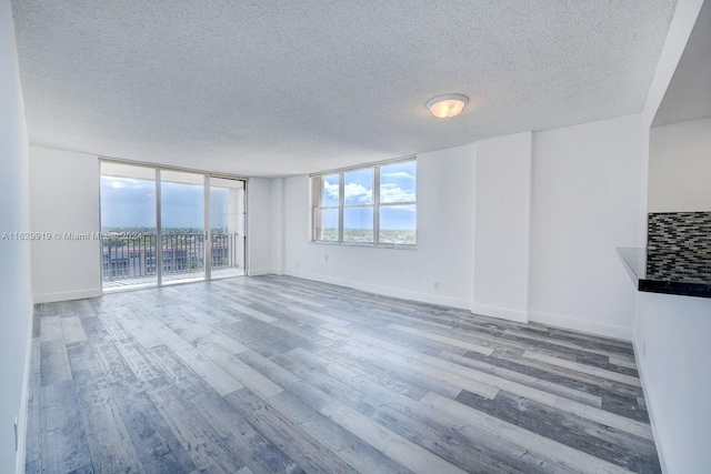 unfurnished living room with hardwood / wood-style flooring, expansive windows, and a textured ceiling