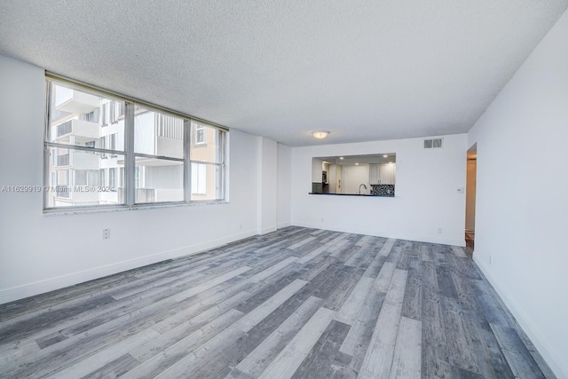 unfurnished living room featuring sink, a textured ceiling, and hardwood / wood-style floors