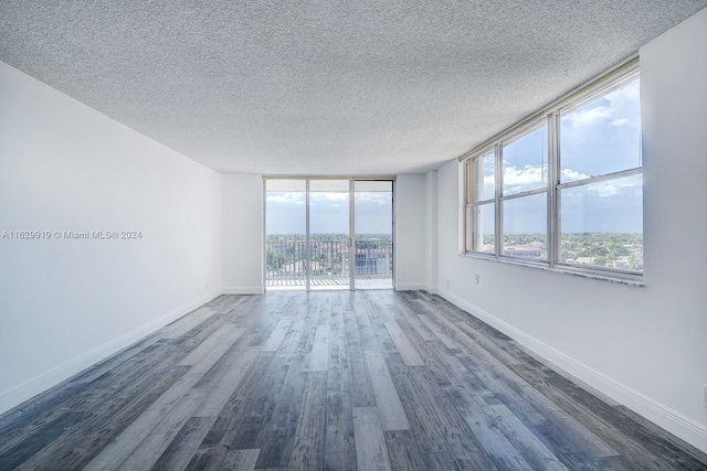 spare room featuring dark hardwood / wood-style flooring, expansive windows, and a textured ceiling