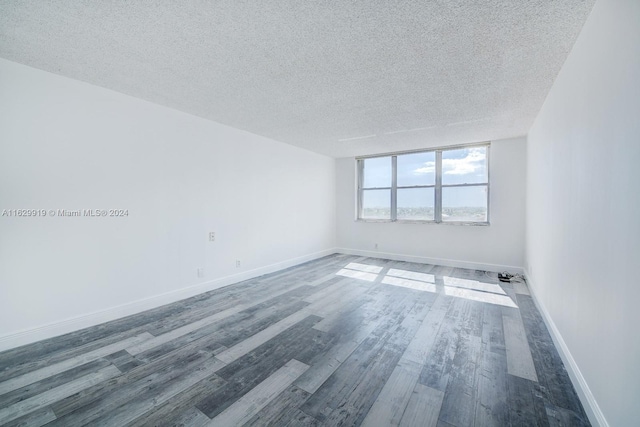 empty room featuring wood-type flooring and a textured ceiling