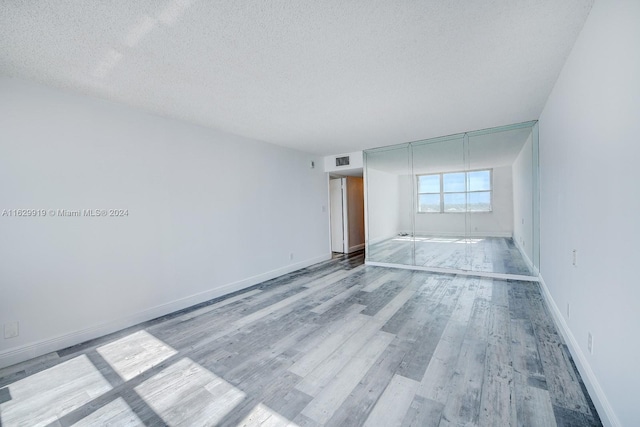 spare room featuring a textured ceiling and hardwood / wood-style flooring