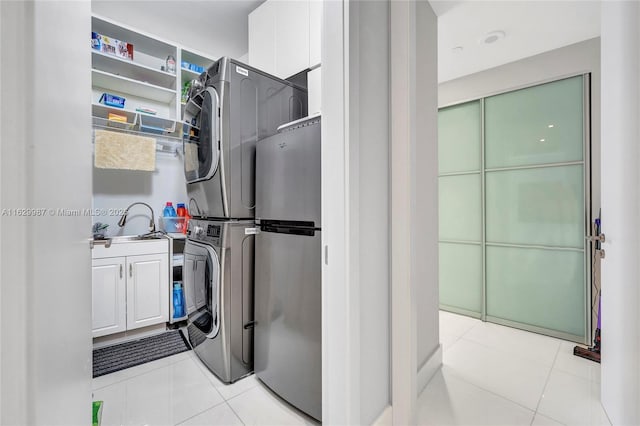 clothes washing area featuring cabinets, stacked washing maching and dryer, and light tile patterned flooring