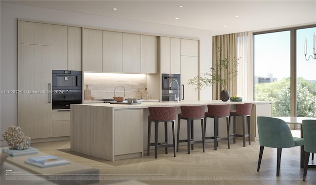 kitchen featuring multiple ovens, black double oven, light parquet flooring, and a center island with sink