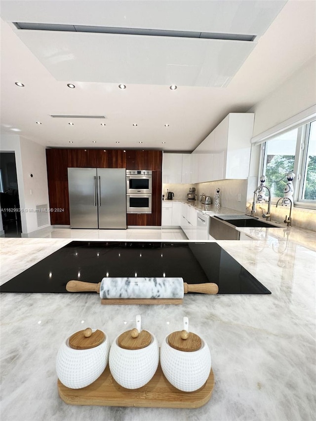 kitchen featuring decorative backsplash, appliances with stainless steel finishes, dark brown cabinets, sink, and white cabinets