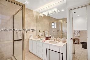 bathroom with vanity, tile walls, tile patterned flooring, and a shower with door