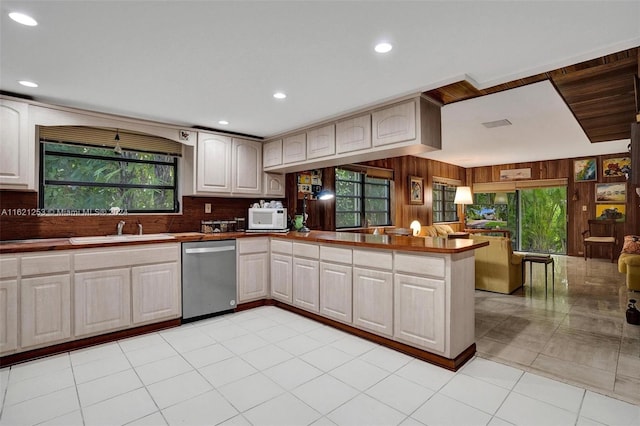 kitchen featuring tasteful backsplash, dishwasher, kitchen peninsula, sink, and light tile patterned flooring