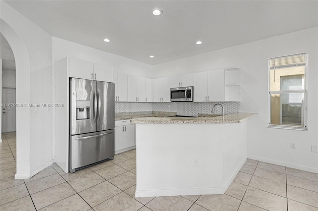 kitchen with white cabinetry, light tile patterned floors, appliances with stainless steel finishes, kitchen peninsula, and decorative backsplash