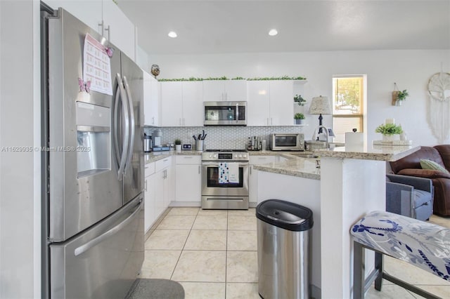 kitchen with white cabinetry, appliances with stainless steel finishes, a breakfast bar area, and kitchen peninsula