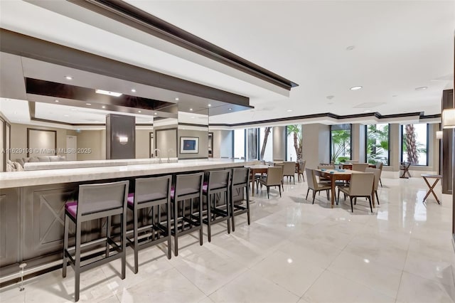 bar with a tray ceiling, ornamental molding, and light tile patterned flooring