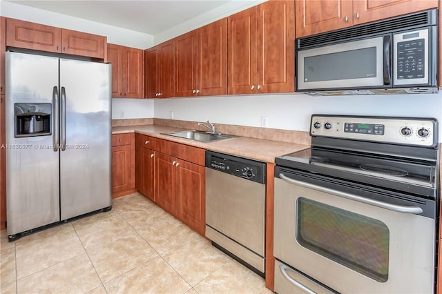 kitchen with light tile patterned flooring, stainless steel appliances, and sink