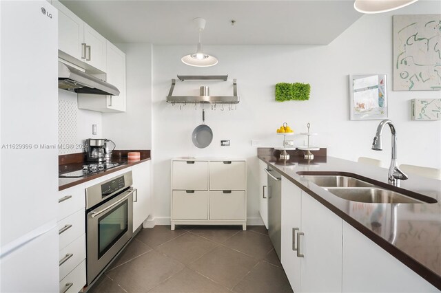 3301 NE 1st Ave Unit M0705, Miami, FL 33137 - kitchen featuring dark tile patterned flooring, dark countertops, stainless steel appliances, under cabinet range hood, and a sink