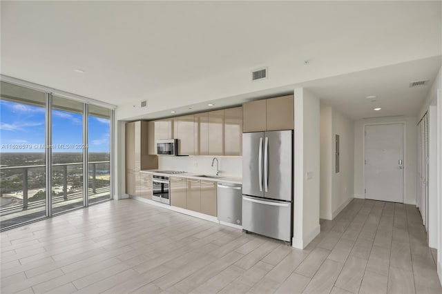 kitchen featuring sink, expansive windows, backsplash, and stainless steel appliances