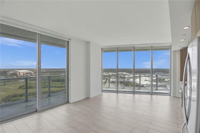 unfurnished room with a wall of windows and a healthy amount of sunlight