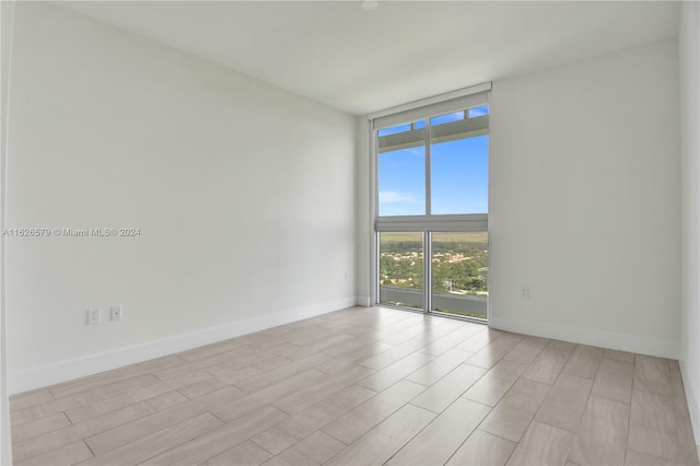 spare room with light hardwood / wood-style floors and a wall of windows